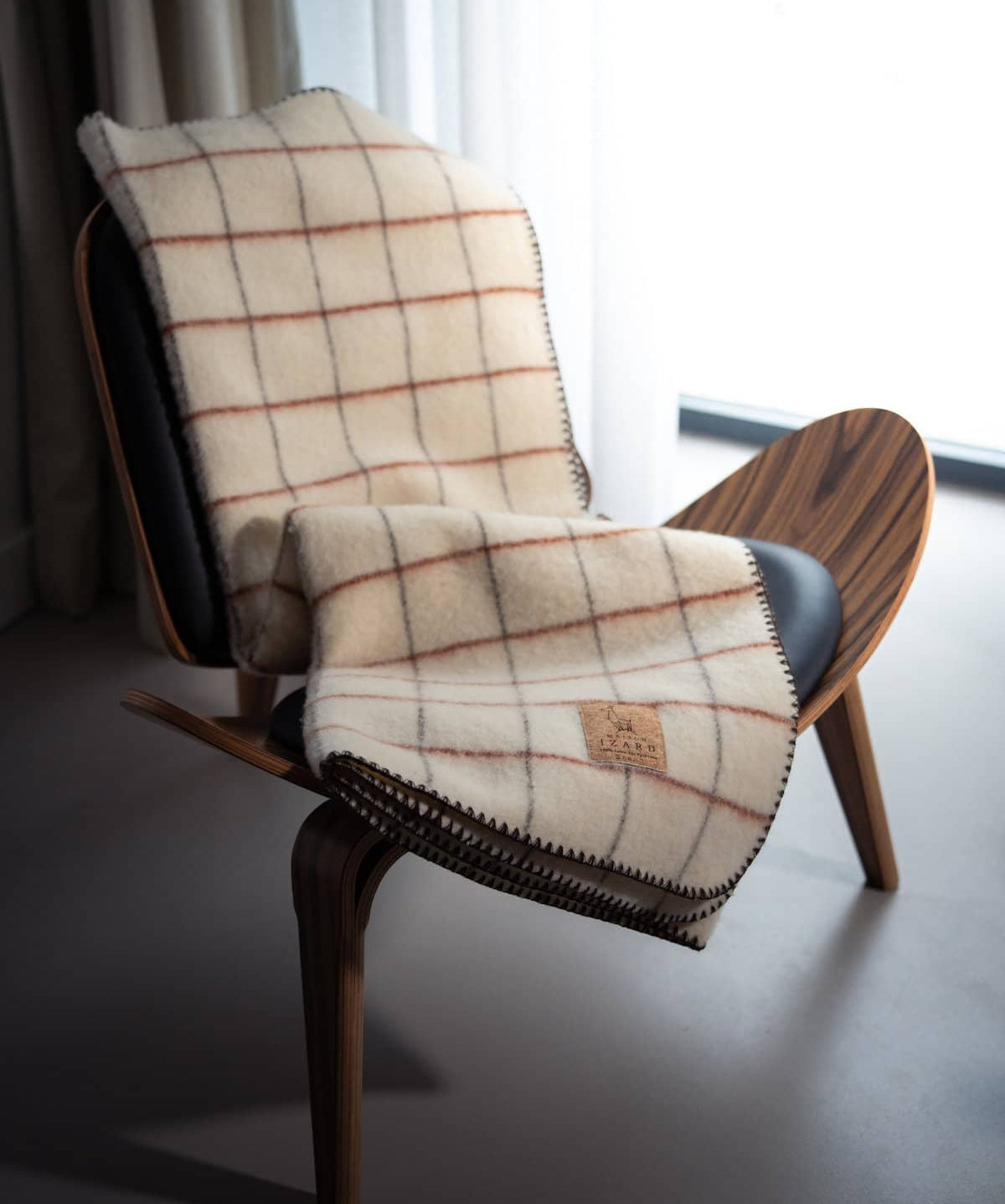 Plaid Calou laine française écru à carreaux terracotta et marron posé sur un canapé