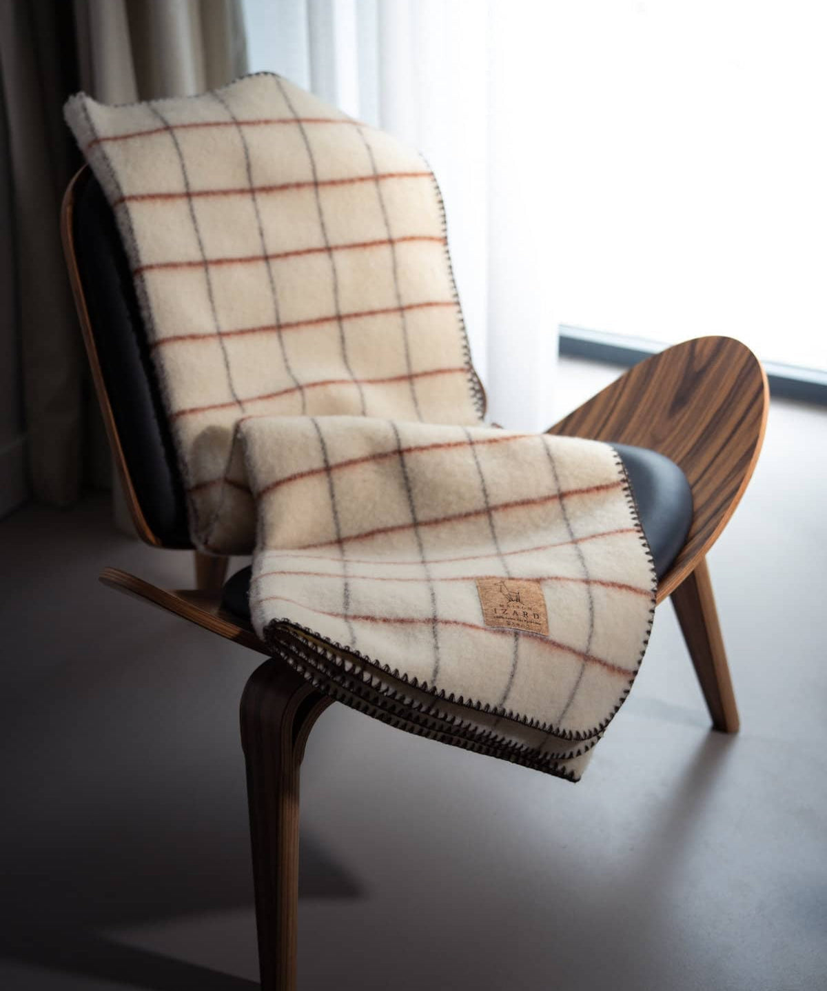 Plaid Calou laine française écru à carreaux terracotta et marron posé sur un canapé